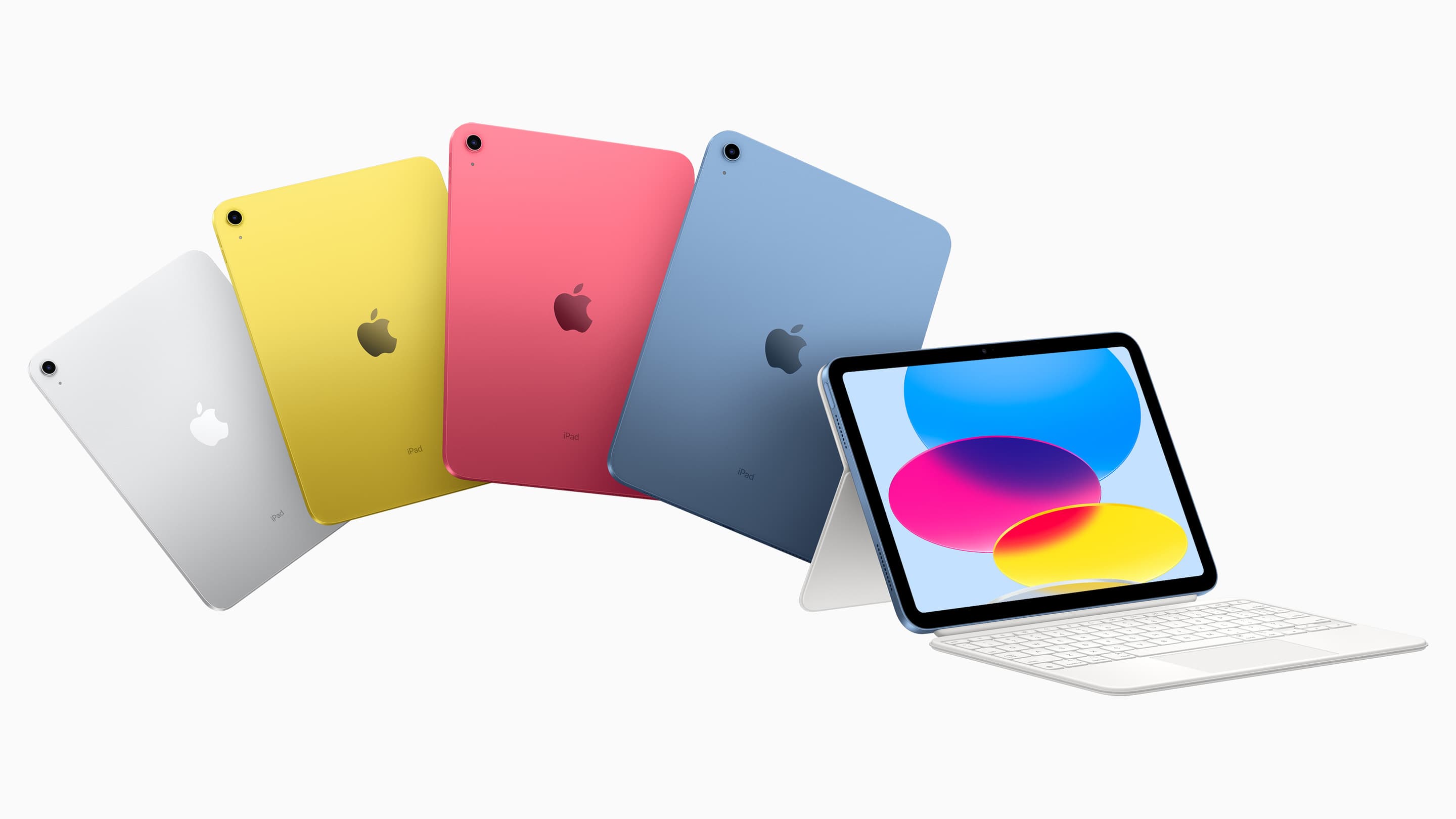 Fire iPad-modeller i sølv, gul, rosa og blå, ved siden av en iPad på hvit Magic Keyboard Folio.