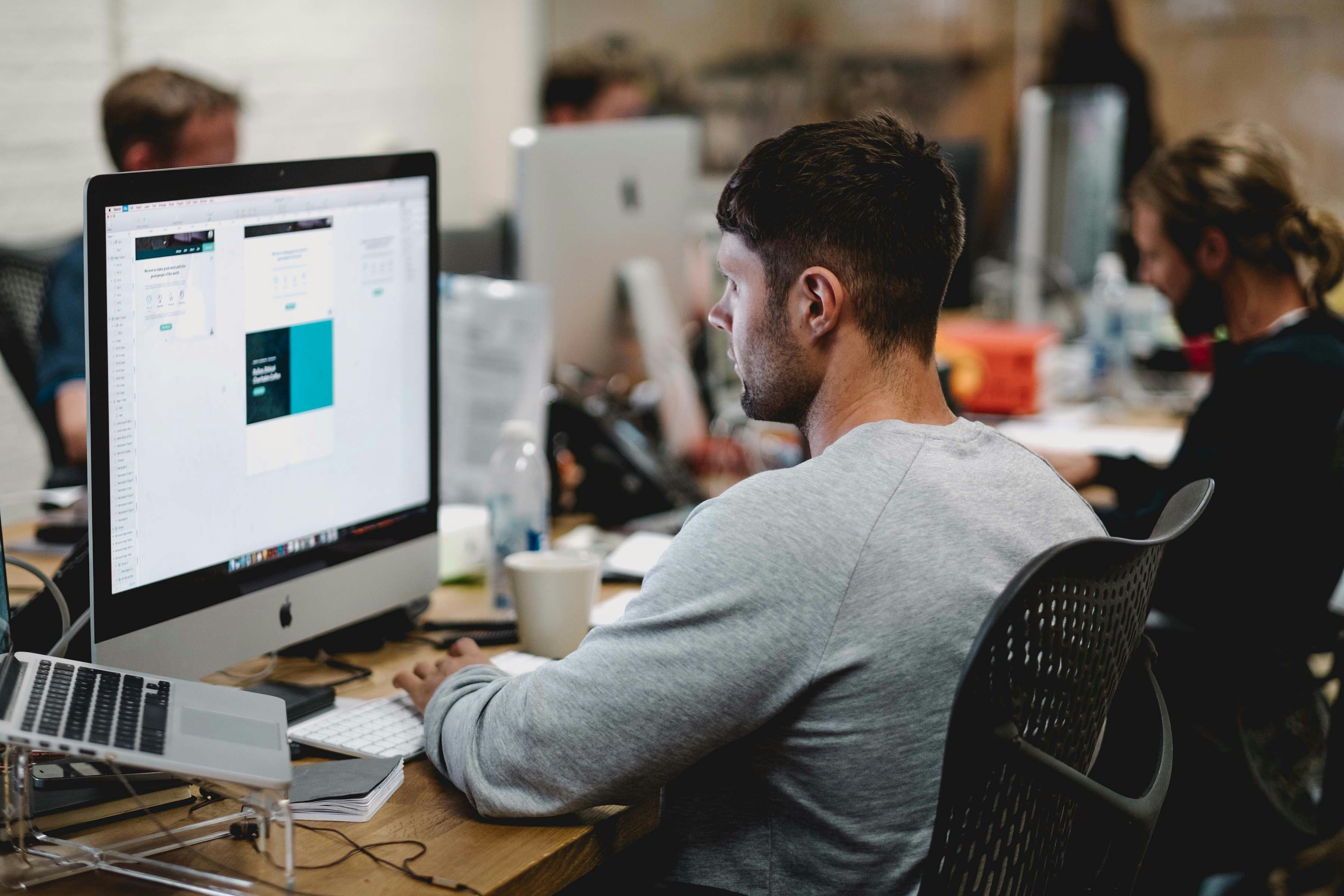 a man sitting behind his computer desk at a design studio