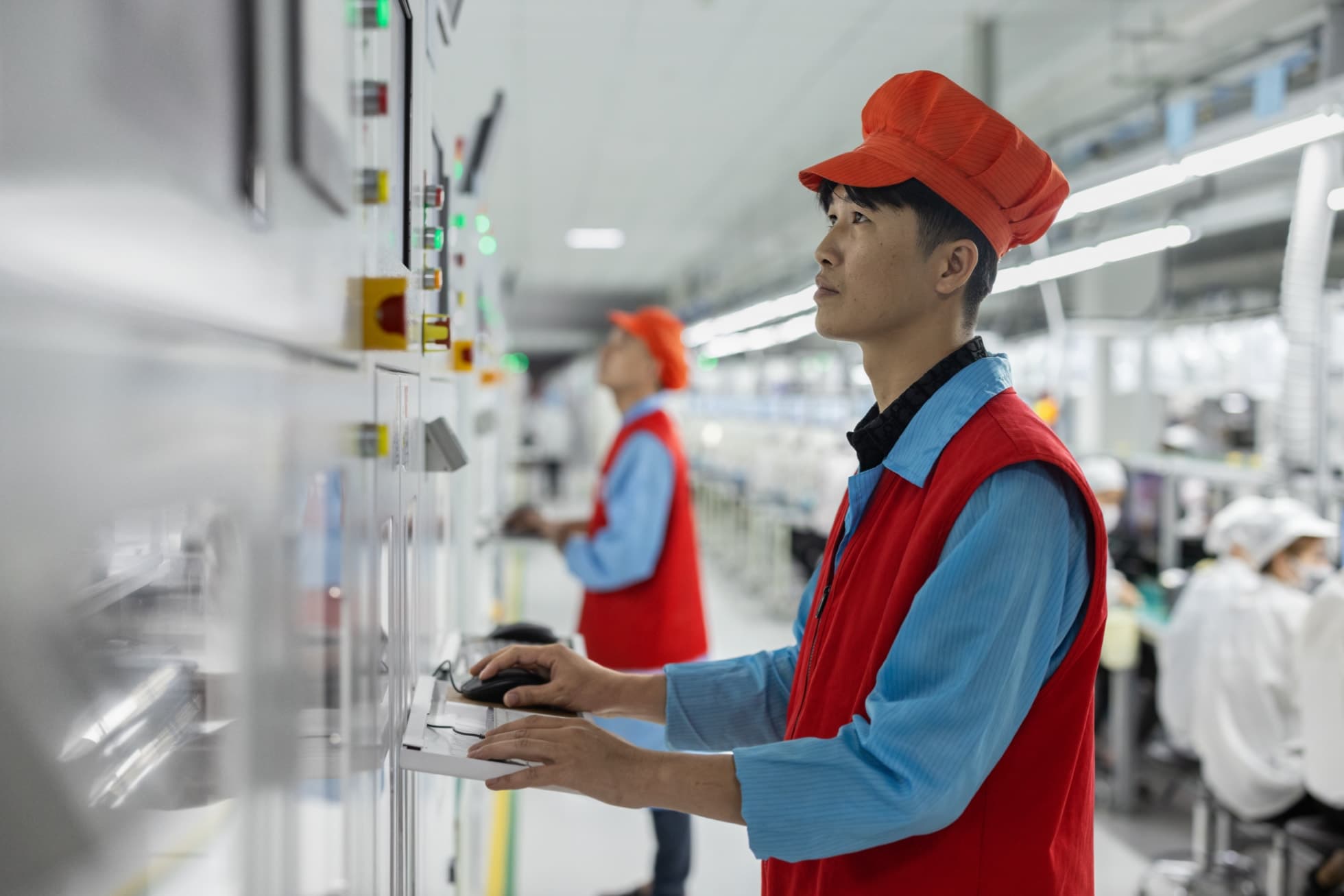 En leverandøransatt betjener et kontrollpanel ved en produksjonslinje i Vietnam.