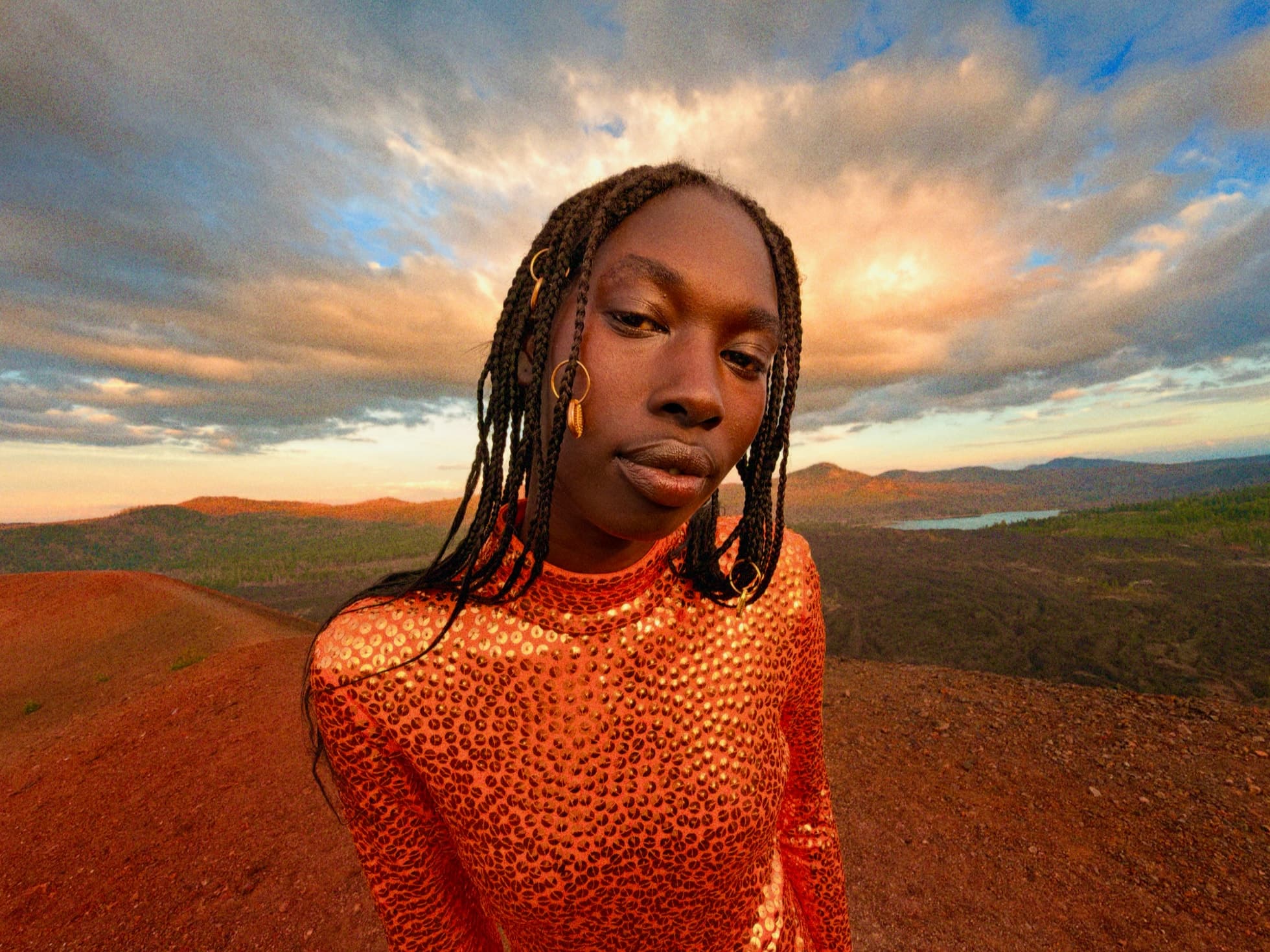 Person i oransje antrekk i et landskap, behandlet med Fotostiler på iPhone Duo.