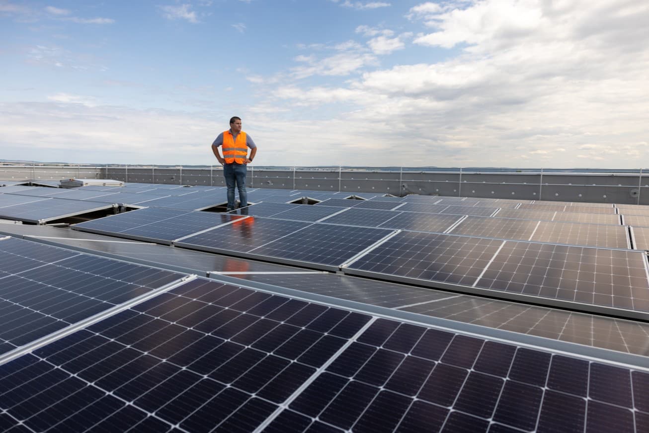 En medarbeider står blant solcellepaneler i Apples leverandørprogram for ren energi.