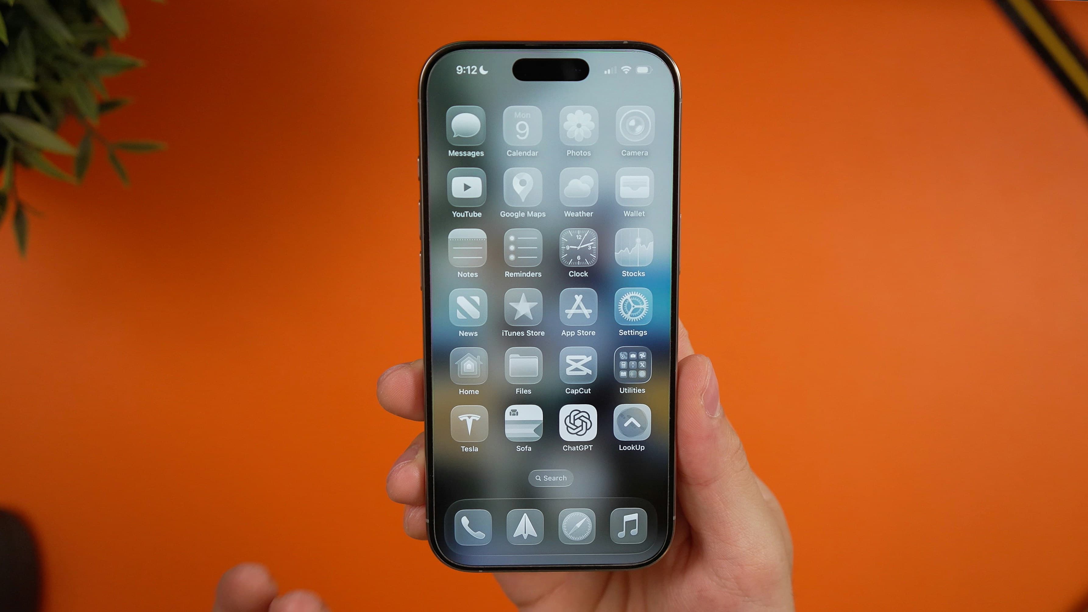 person holding iPhone showing home screen with liquid glass