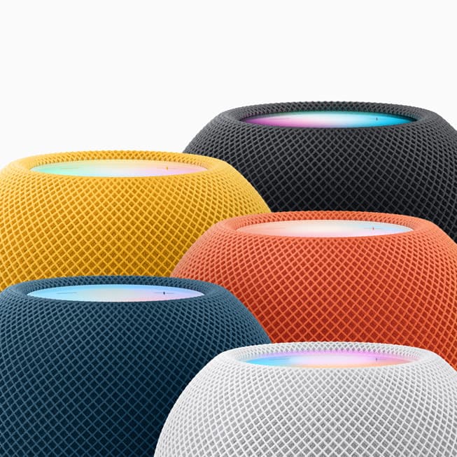 HomePod mini i alle farger – midnatt, gul, oransje, blå og hvit – tett samlet mot lys bakgrunn