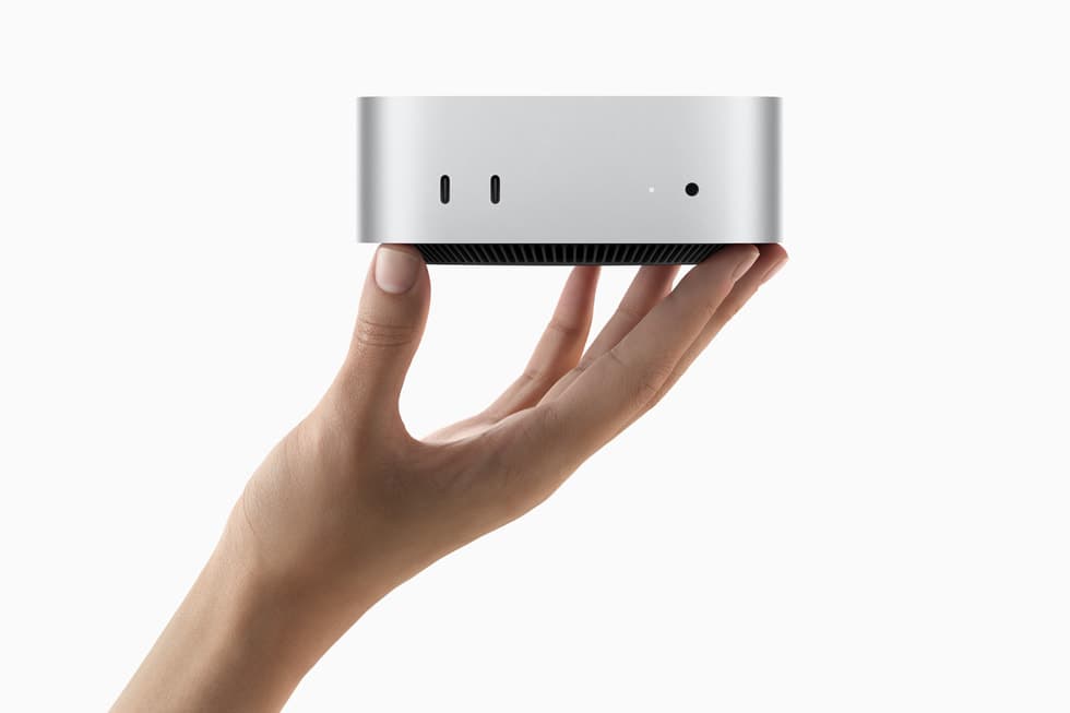 En hånd holder den kompakte Mac mini, som så vidt dekker håndflaten.