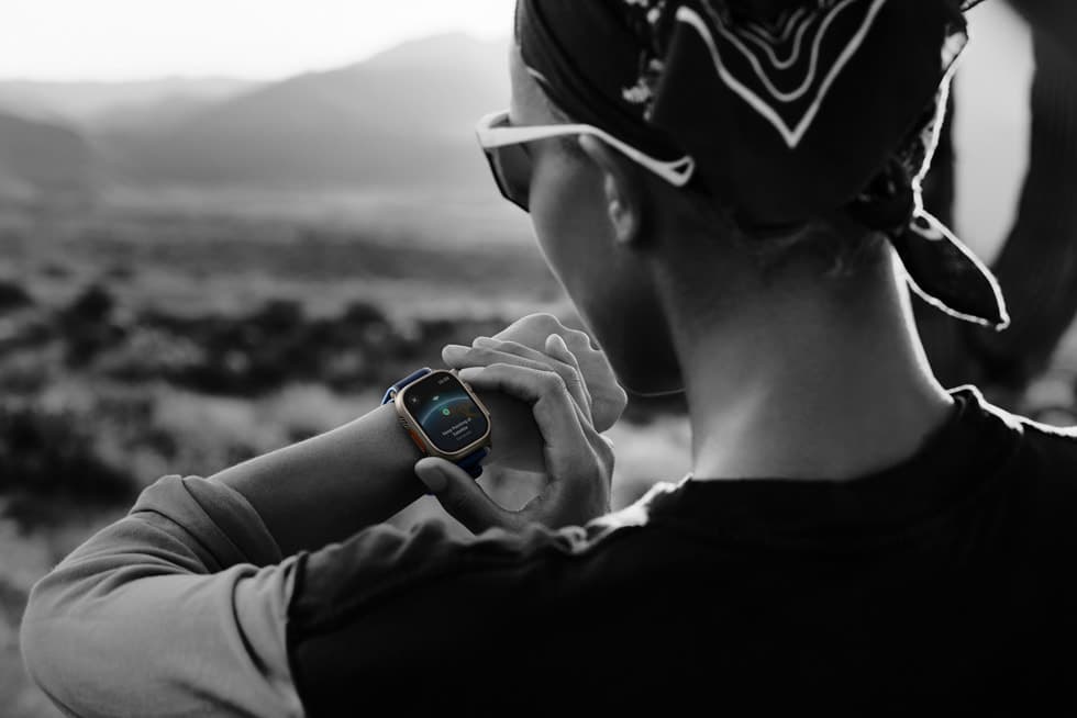 Person paa fjelltur bruker Apple Watch Ultra 3, som viser et satellittmeldings-grensesnitt paa skjermen