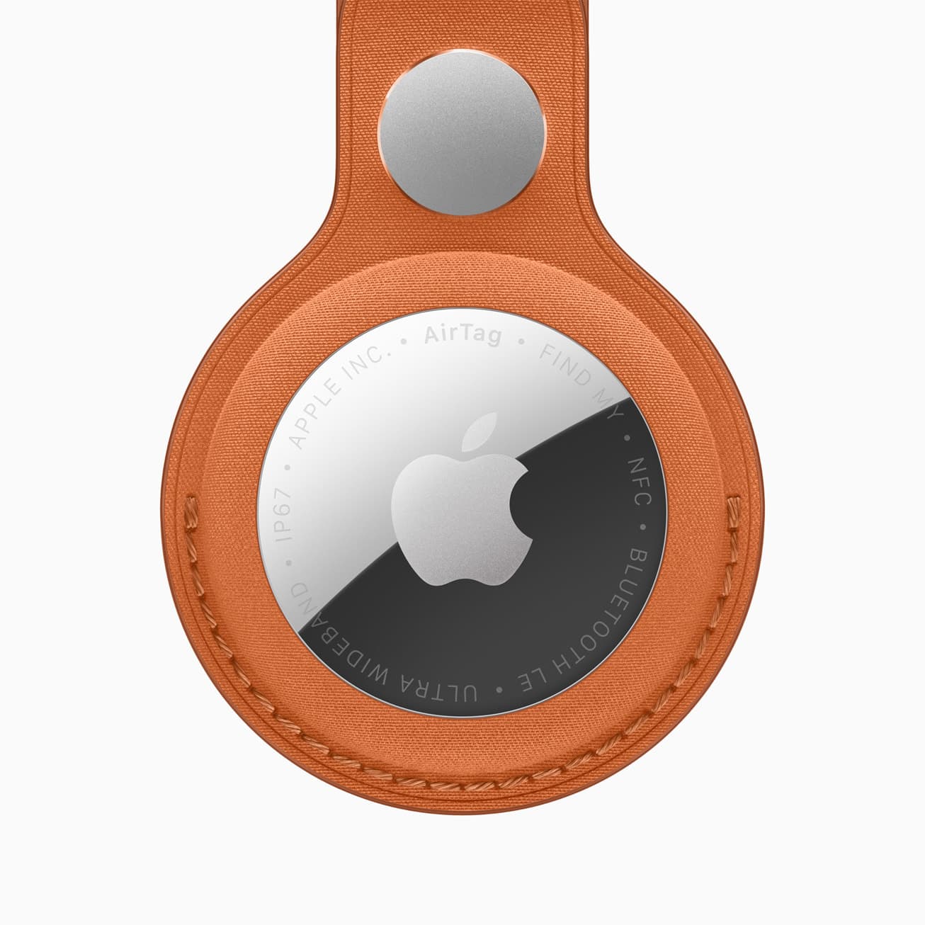 En AirTag i en oransje FineWoven-nøkkelring, med Apple-logoen og AirTag-gravering synlig på den blanke fronten