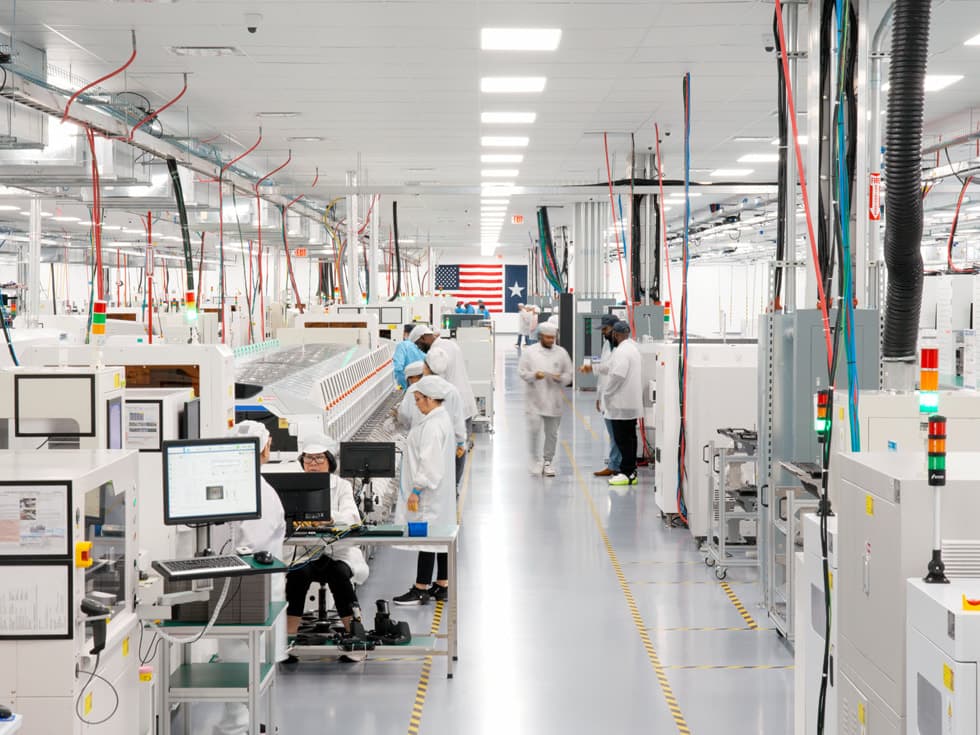 Ansatte i renromsfrakker jobber langs en samlebånd-linje i Apples produksjonsanlegg i USA