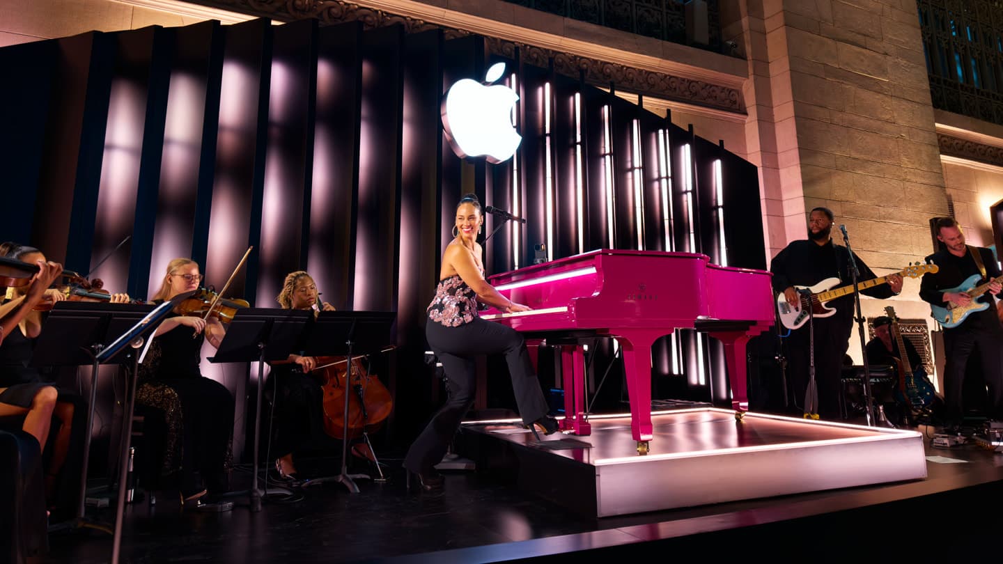 Alicia Keys spiller piano på en scene full av musikere i Apple Grand Central.