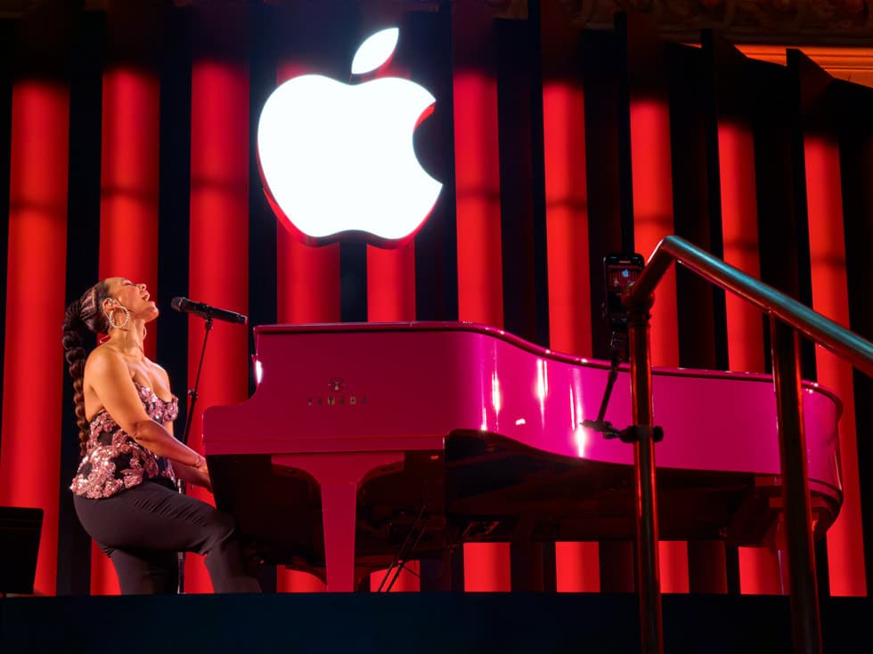 Alicia Keys spiller på et rosa flygel under en opplyst Apple-logo under jubileumskonserten i Apple Store Grand Central i New York