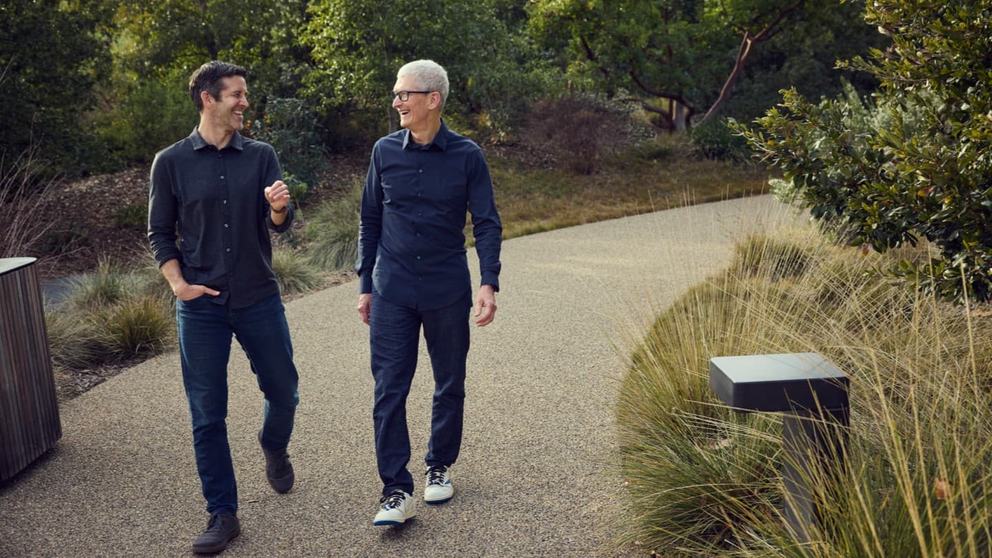 John Ternus og Tim Cook gaar sammen og prater paa et utesti ved Apple Park